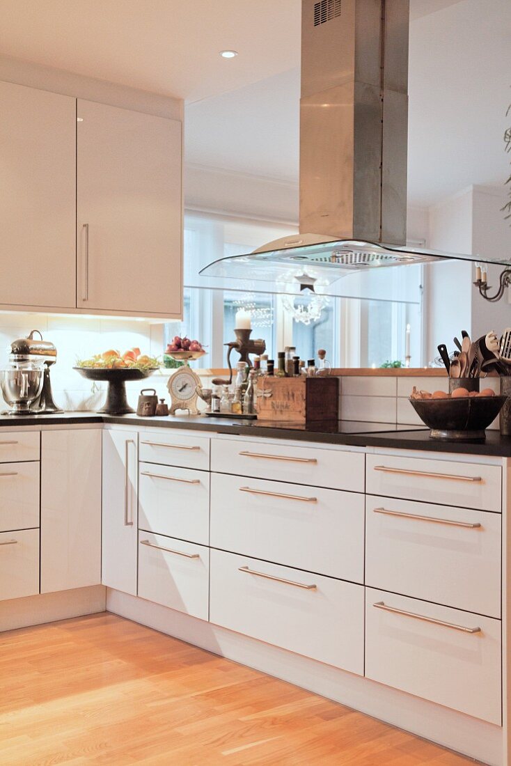 Vintage utensils in elegant, L-shaped fitted kitchen with extractor hood