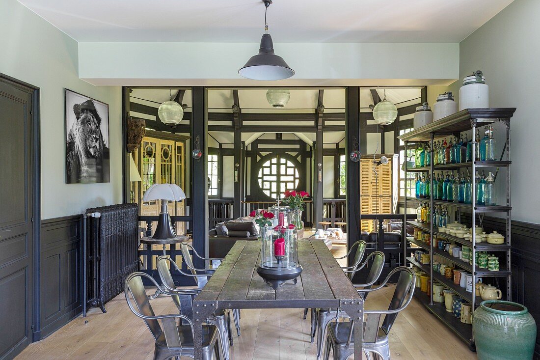 Eclectic furnishings in half-timbered house with open metal shelves, rustic table and classic chairs
