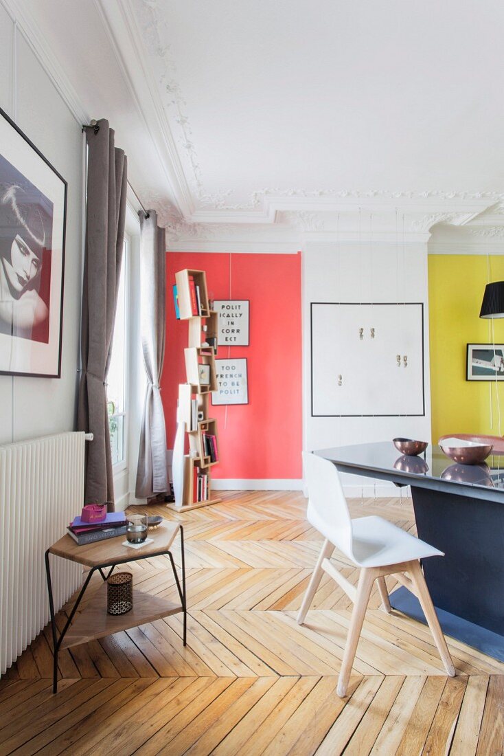 Dining area in restored period apartment with stucco ceiling, herringbone parquet floor and colourful accent walls
