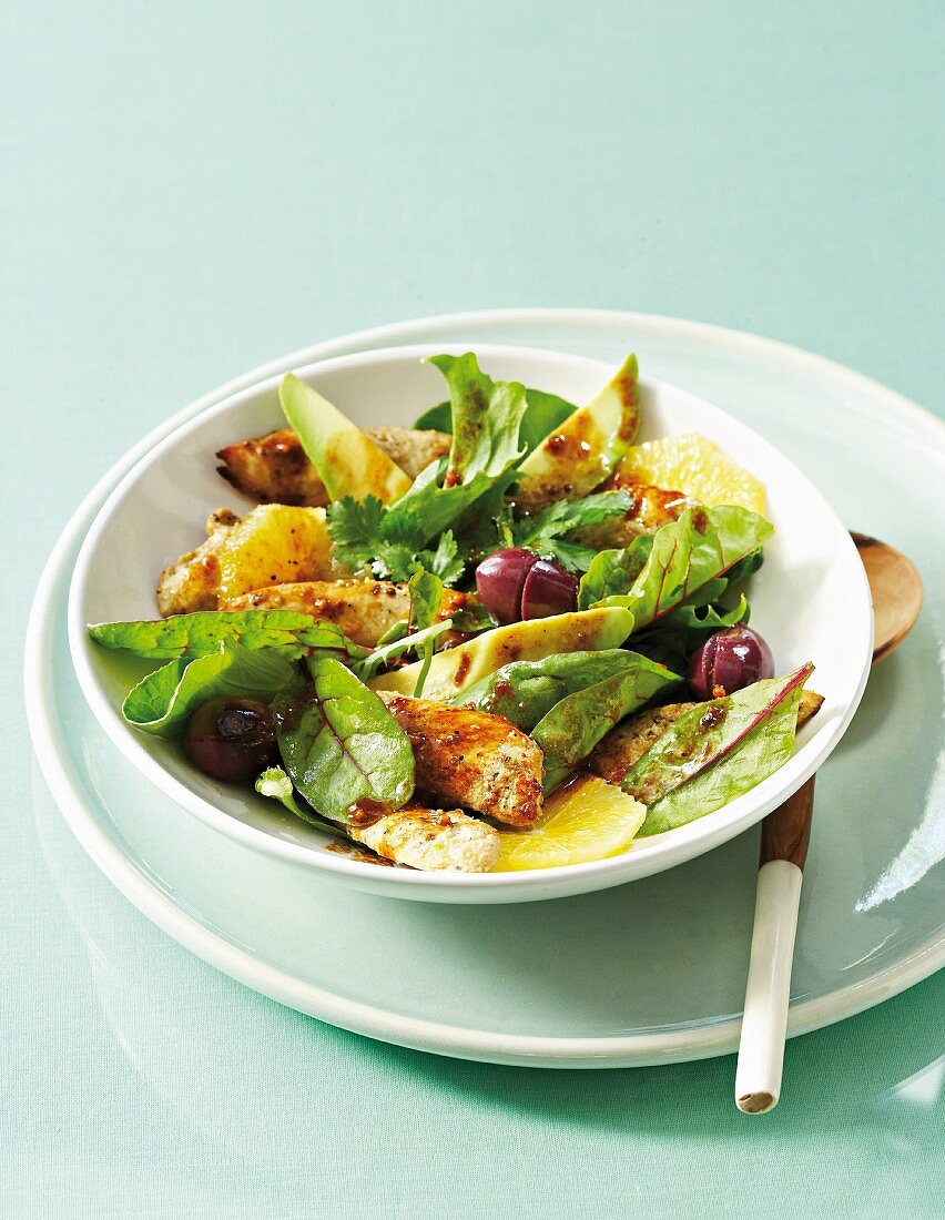 Warm summer salad with chicken, avocado, olives and orange