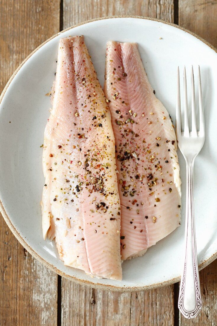 Smoked fillets of trout with pepper on a plate (seen from above)