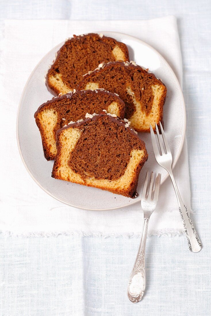 Several slices of marble cake with chocolate icing on a plate