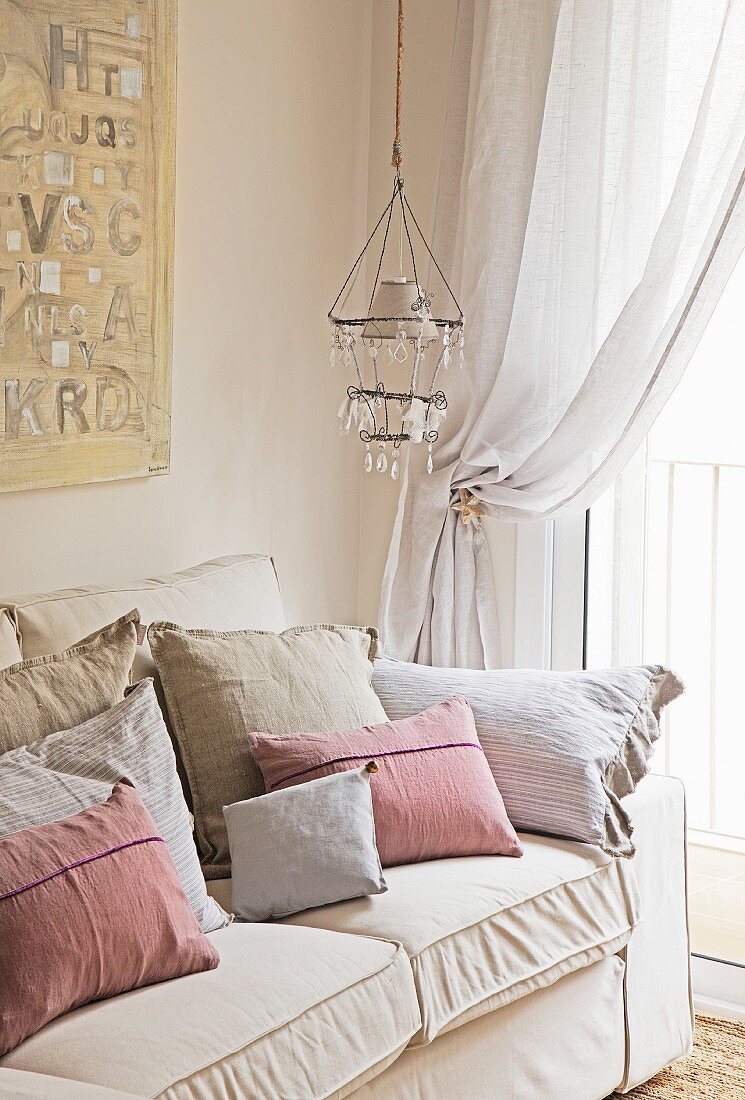 Piles of various scatter cushions on sofa in corner of romantic room