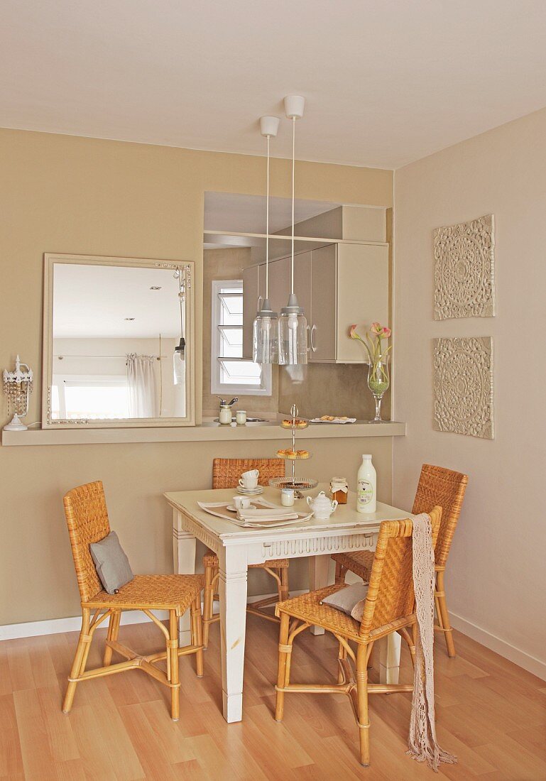 Dining table and cane chairs below serving hatch leading to kitchen