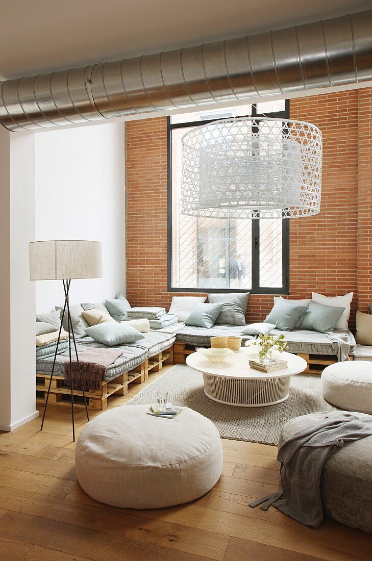 Elegante Lounge in Loftwohnung mit Ziegelwand und Holzpalettenmöbeln
