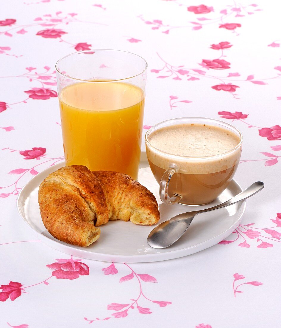 Breakfast with cappuccino, a croissant and orange