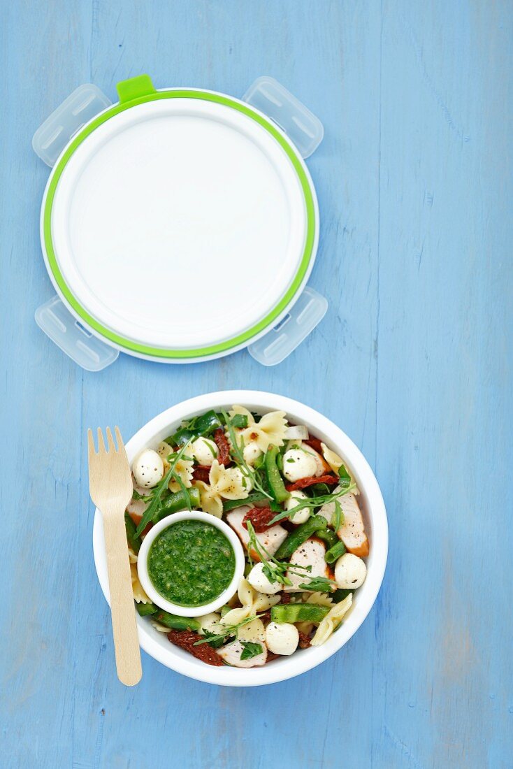 A lunchbox containing pasta & chicken salad with green pepper, dried tomatoes, rocket and mozzerella