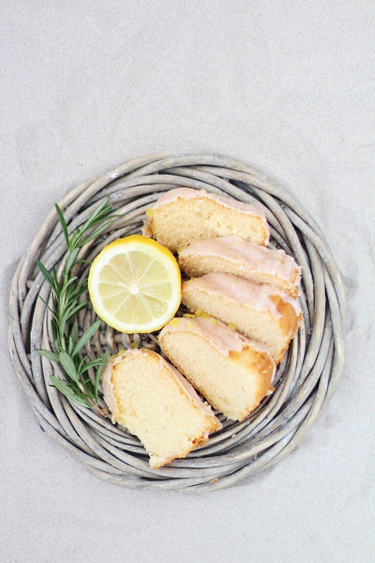 Sliced Bundt cake in a wicker basket with lemon and rosemary