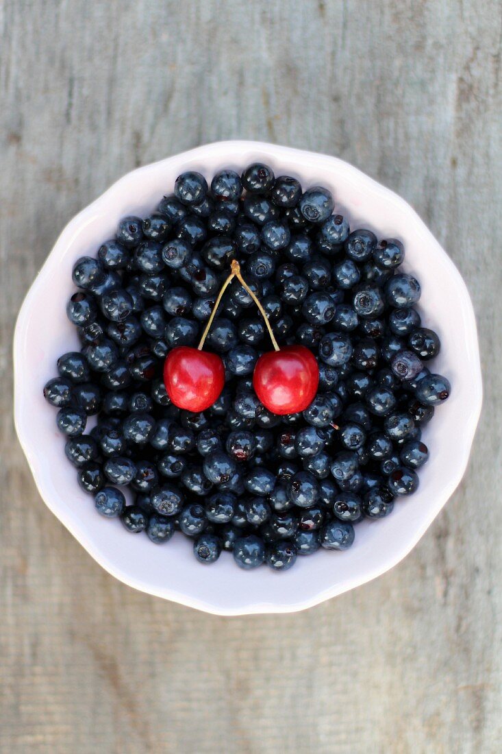 Blueberries and a pair of cherries in a bowl