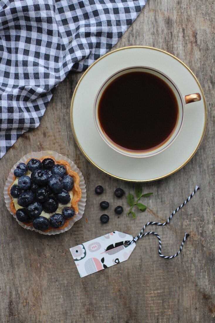 A cup of coffee and a blueberry tartlet