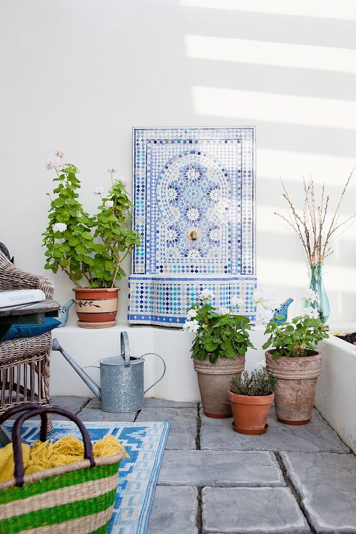 Sommerliche Loggia mit kunsthandwerklichem Waschbecken aus Mosaiksteinen und Wandarmatur in Wandornament