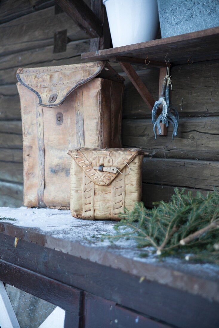 Two birch-bark bags on table outside wooden house