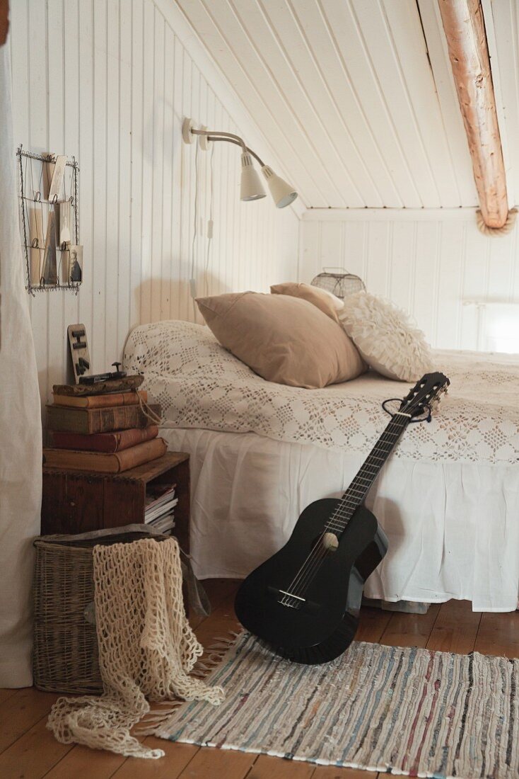 Black guitar leaning against bed in rustic romantic bedroom