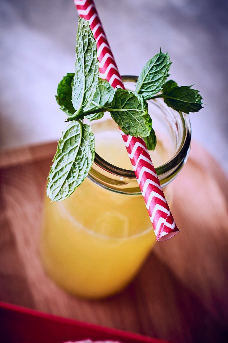 Fruchtsaft in Flasche mit frischer Minze und Strohhalm