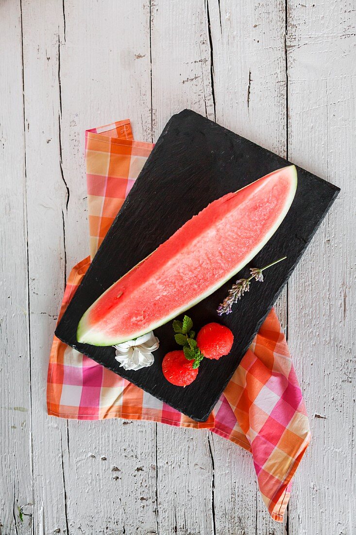 Frische Wassermelone mit Minze und Rosmarin auf Holztisch