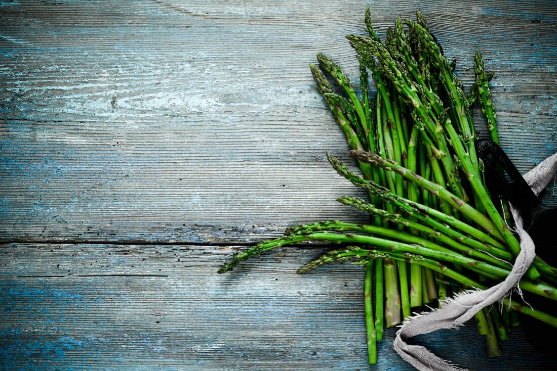 A bunch of green asparagus on a wooden surface