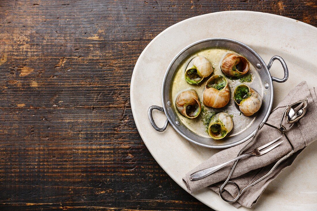 Bourgogne Escargot Snails with garlic herbs butter in aluminum pan on white plate