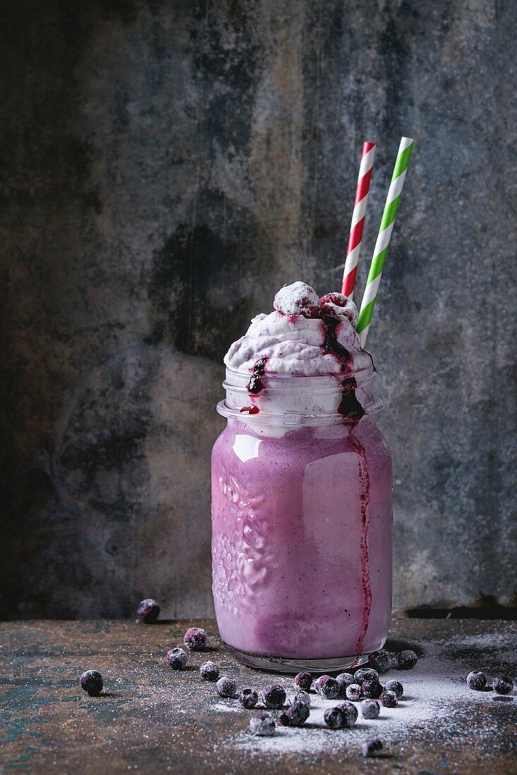 Blueberry smoothie served with whipped cream, berry sauce and fresh berries