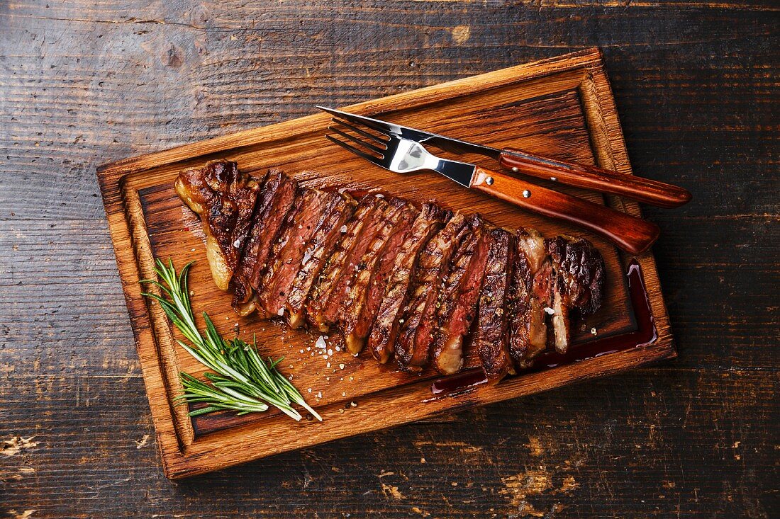 Gegrilltes Striploin Steak in Scheiben geschnitten auf Holzbrett