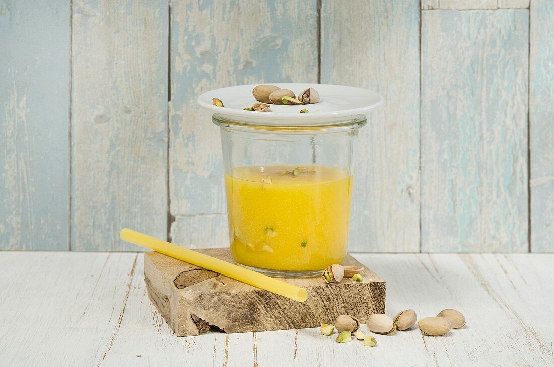 Mango-Apfel-Smoothie im Glas mit Pistazien