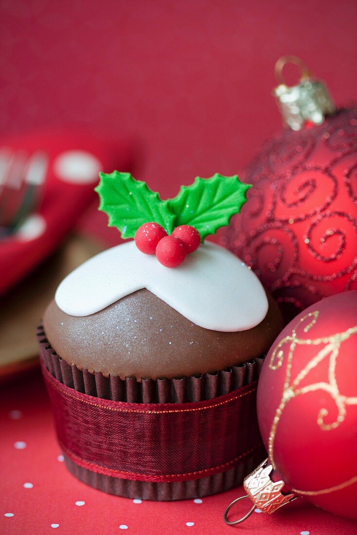 Weihnachts-Cupcake umgeben von roten Weihnachtskugeln