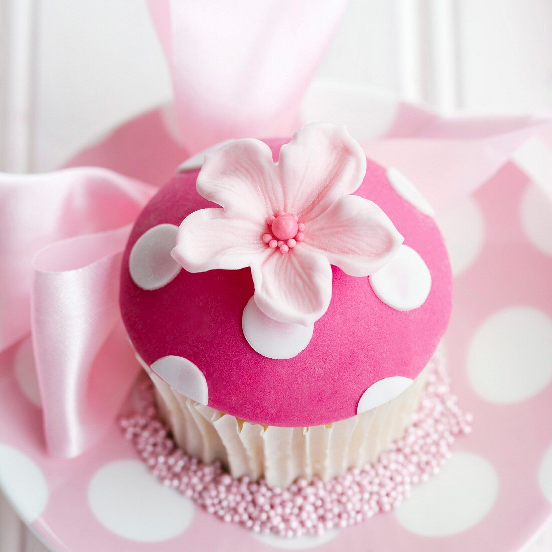 Rosa Cupcake, verziert mit einer Fondantblüte