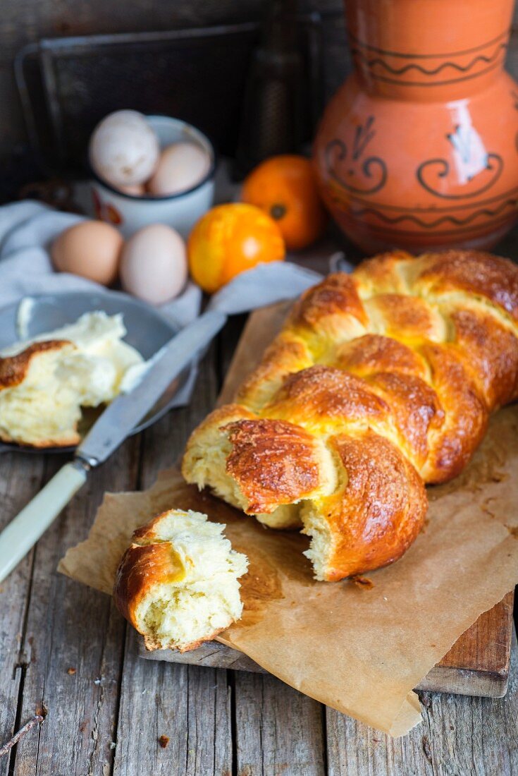 A homemade Hefezopf (sweet bread plait from southern Germany) with orange zest with a chunk broken off for Easter