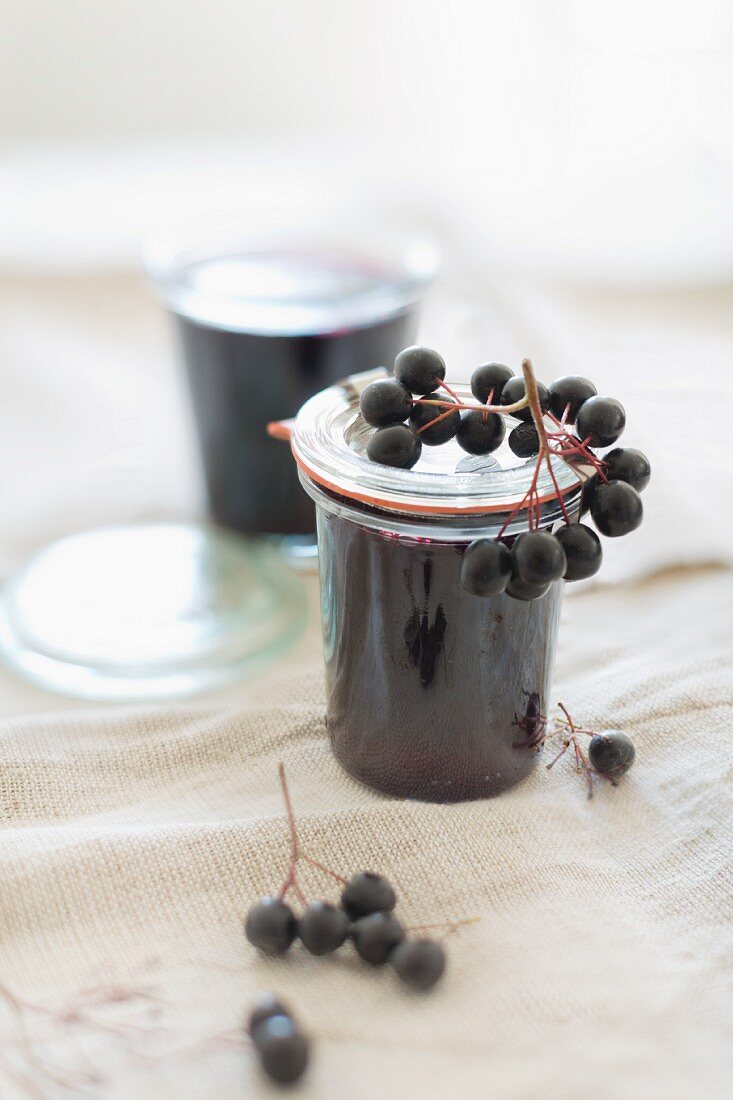 Home-made aronia berry jelly in glass jars with fresh aronia berries