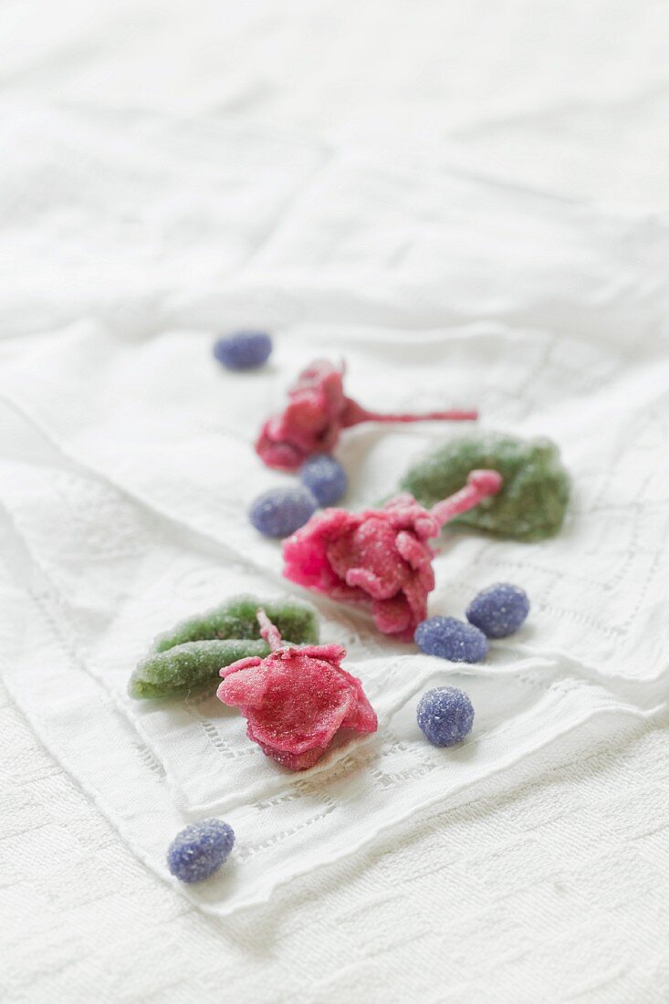 Kandierte Rosenblüten, Veilchenblüten und Pfefferminzblätter auf altem Tuch