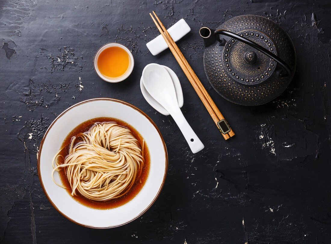 Asian Ramen noodles with broth in bowl and Tea on dark background