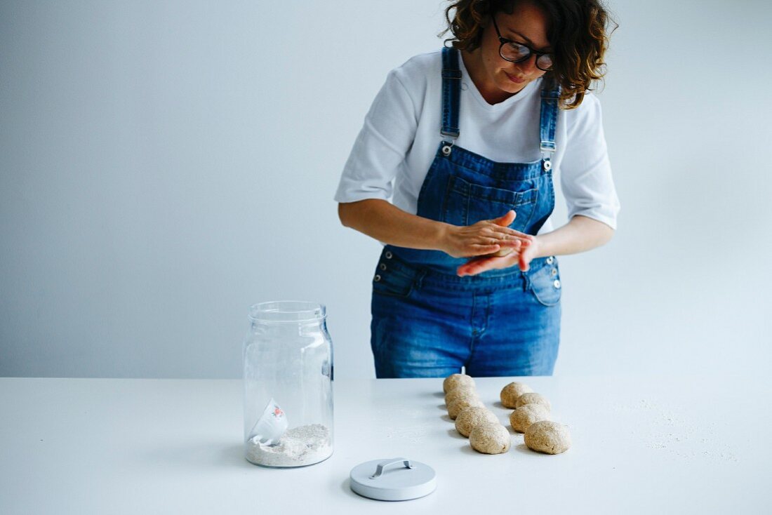Girl forming dough for bagels on a white table