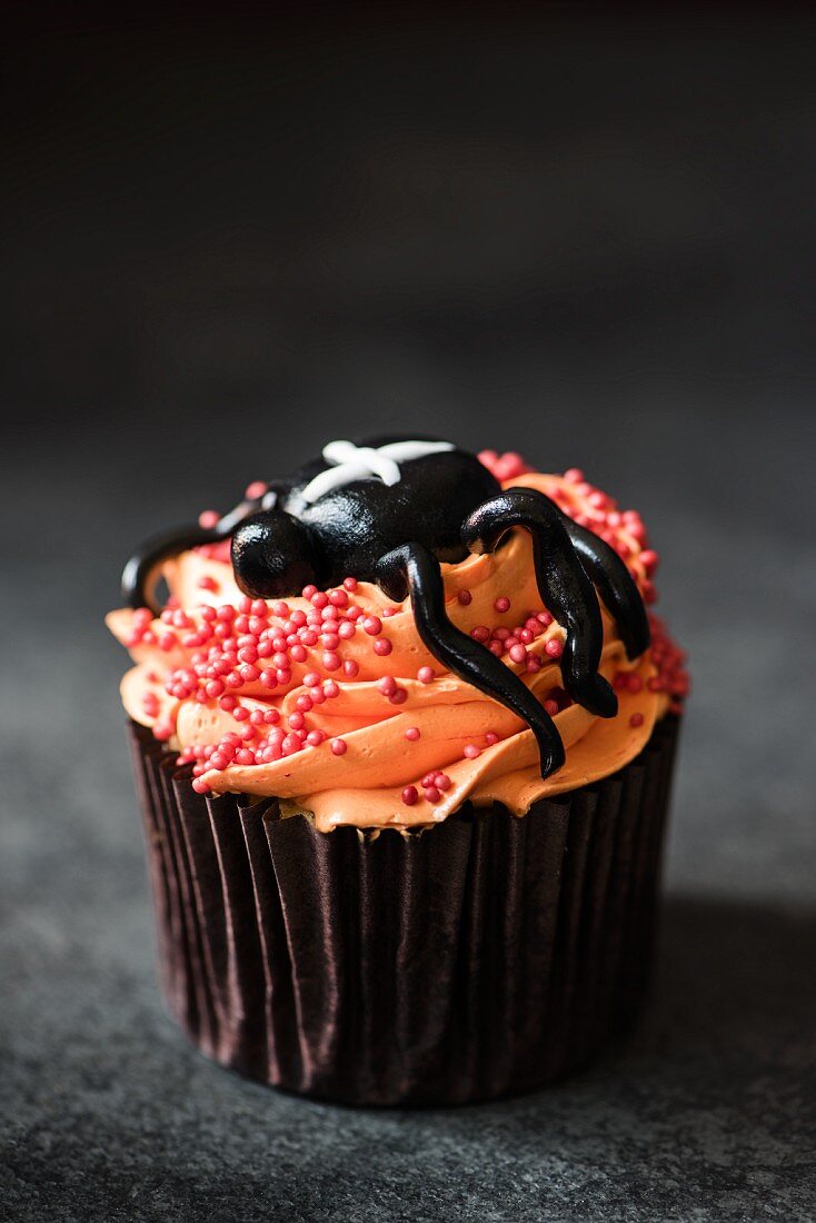Halloween-Cupcake mit orangefarbener Buttercreme und Spinne