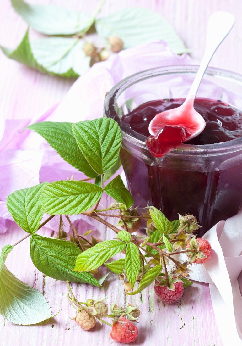 A jar of raspberry jam and fresh raspberries