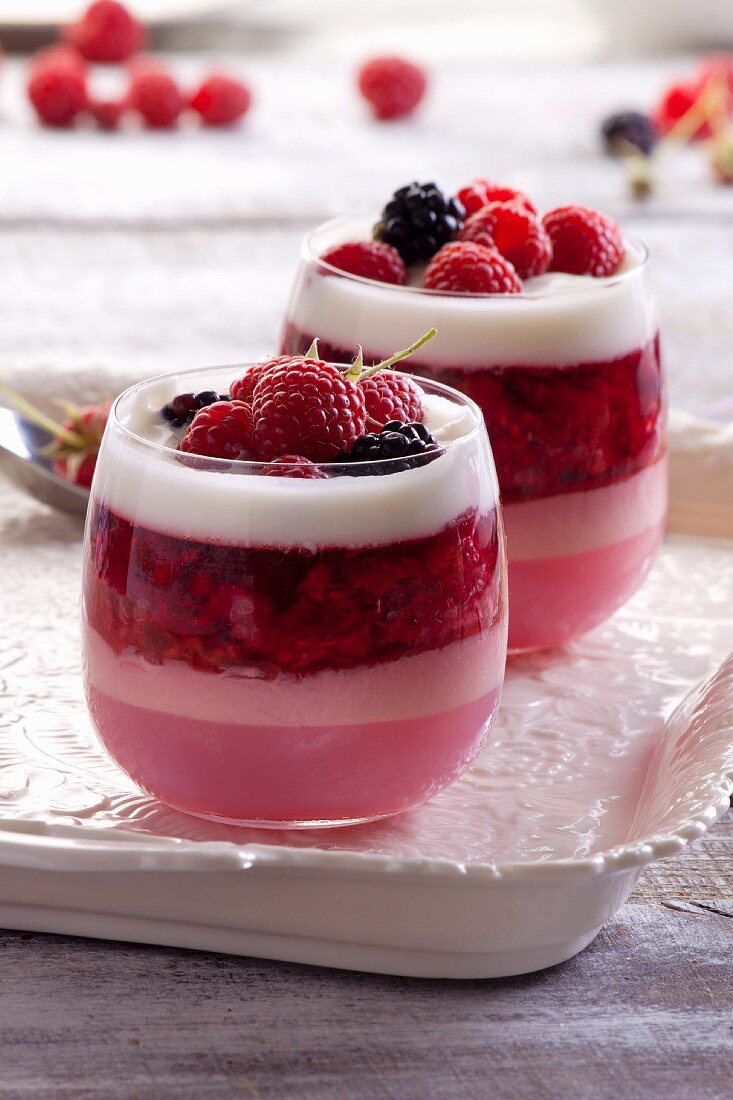 A layered dessert with raspberry mousse, jelly, joghurt and fresh berries