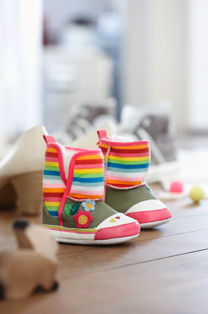 Colourful baby's boots next to other shoes