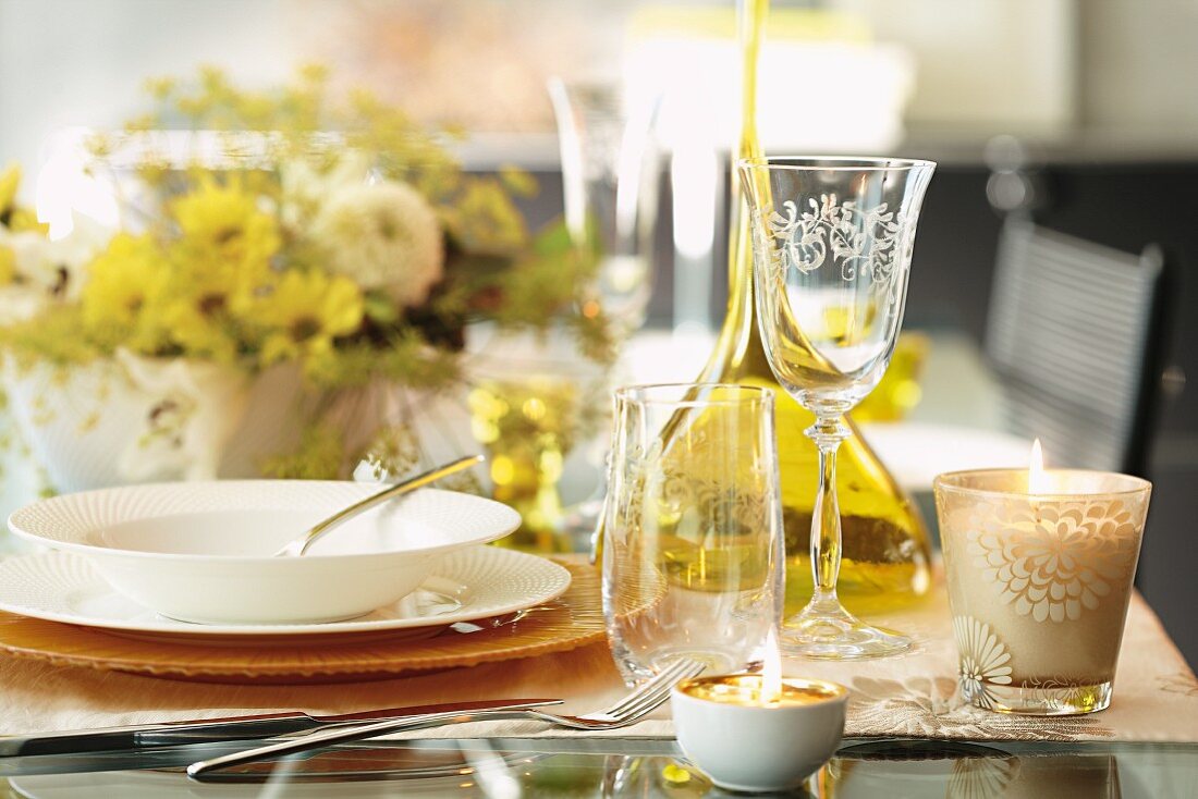 An autumnal set table with glasses, candles and a bouquet of flowers