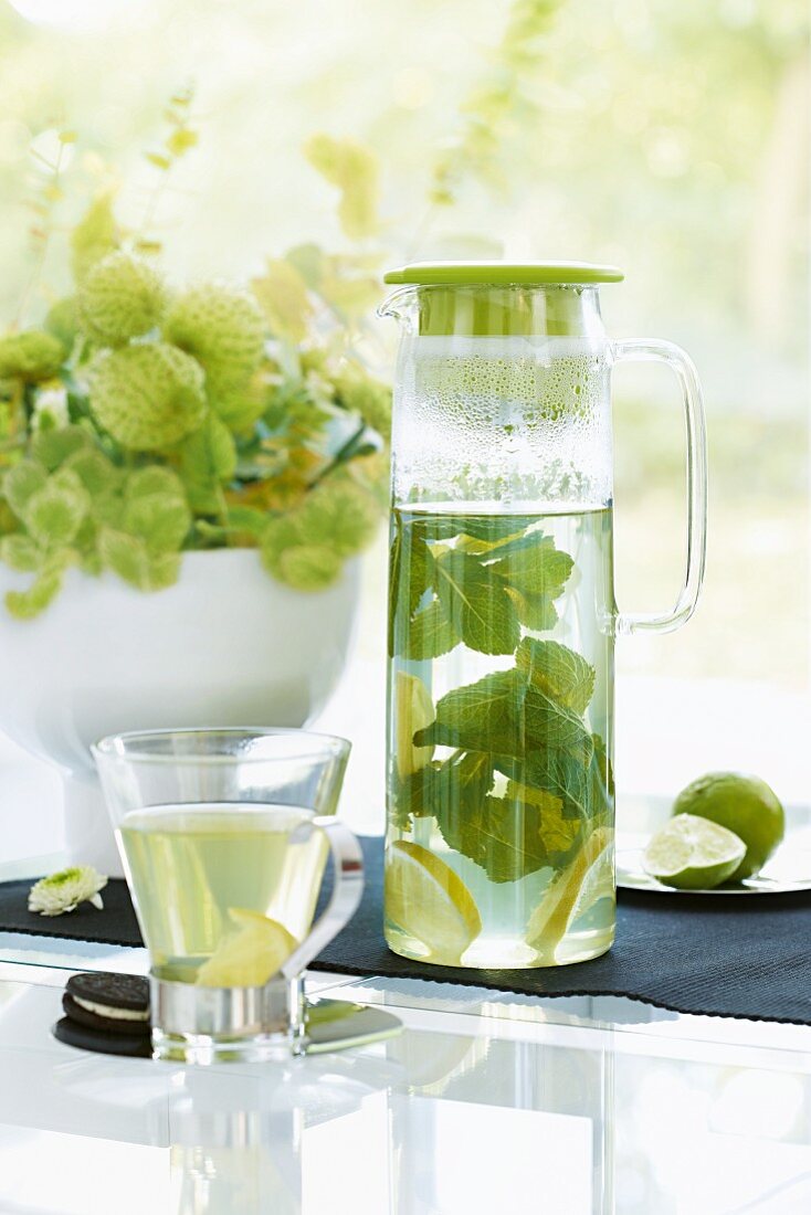 Hot lemonade with mint in a glass jug and tea glass