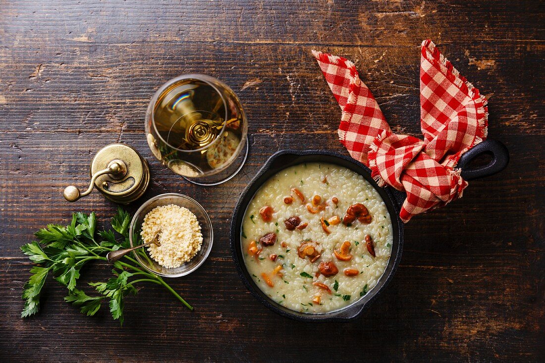 Risotto mit Pfifferlingen in der Pfanne auf Holztisch