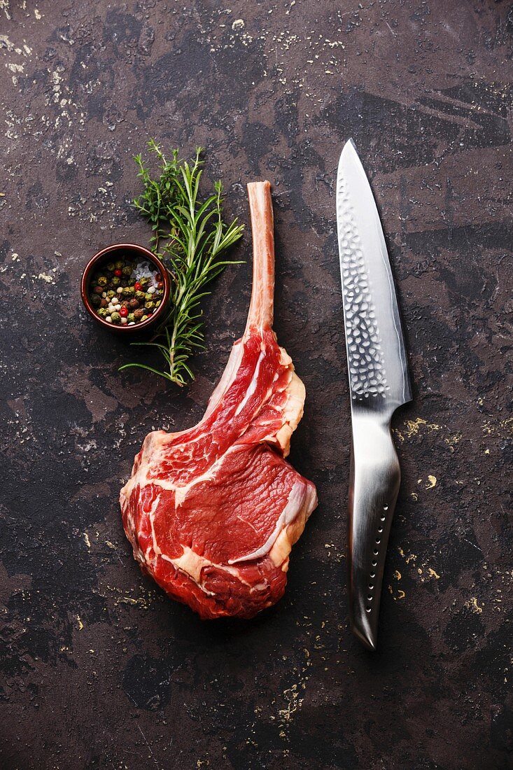 Raw fresh meat Veal rib Steak on bone and kitchen knife on dark background