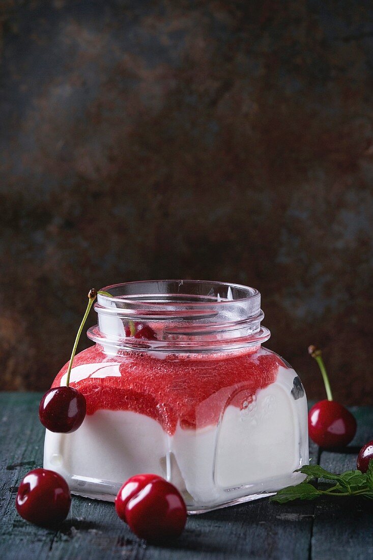Selbst gemachter Joghurt mit Erdbeerpüree und Kirsche, serviert im Glas