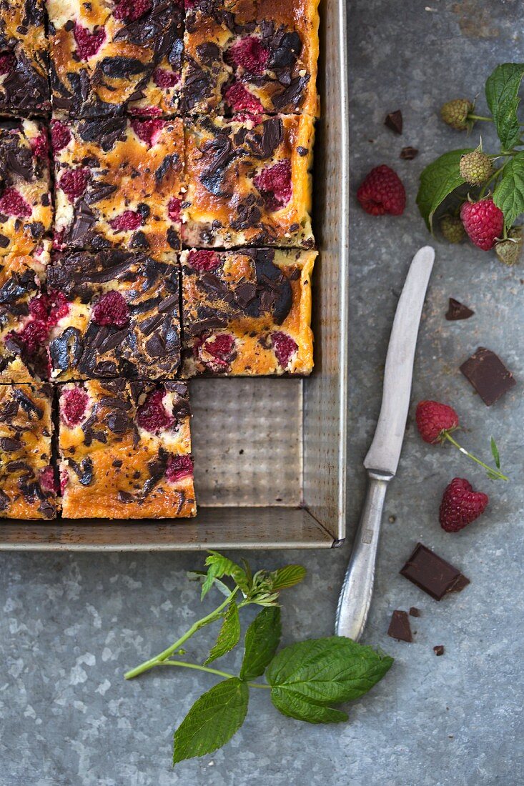 Cheesecake brownies with raspberries in a baking pan (seen from above)