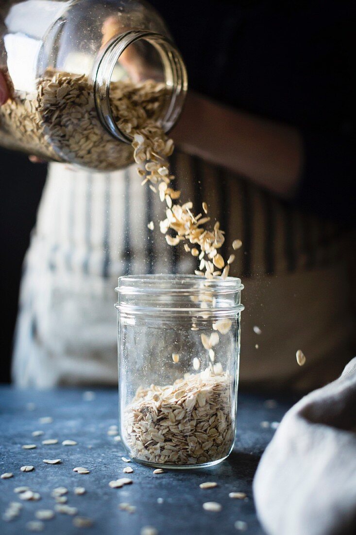 A woman pouring oats it to a jar