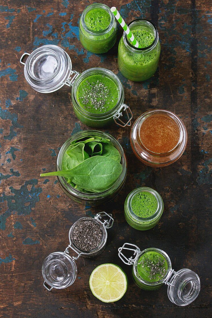 Spinach smoothie in jars served with spinach leaves, chia seeds, honey and lime