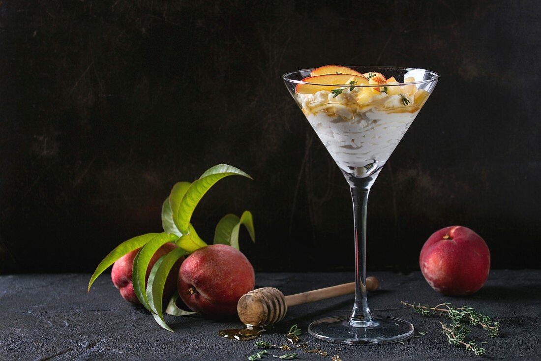 A ricotta dessert with peach, thyme and honey served in a cocktail glass