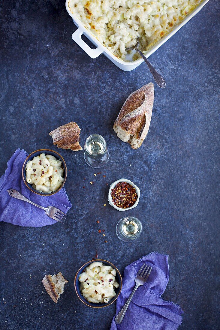 Macaroni and cheese with artichokes in bowls and a baking dish