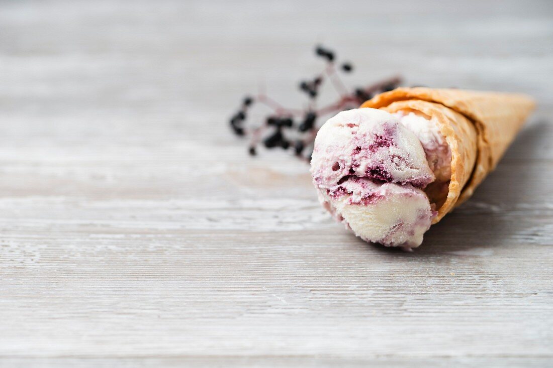 Vanilleeis mit Holunderbeersauce im Waffelhörnchen