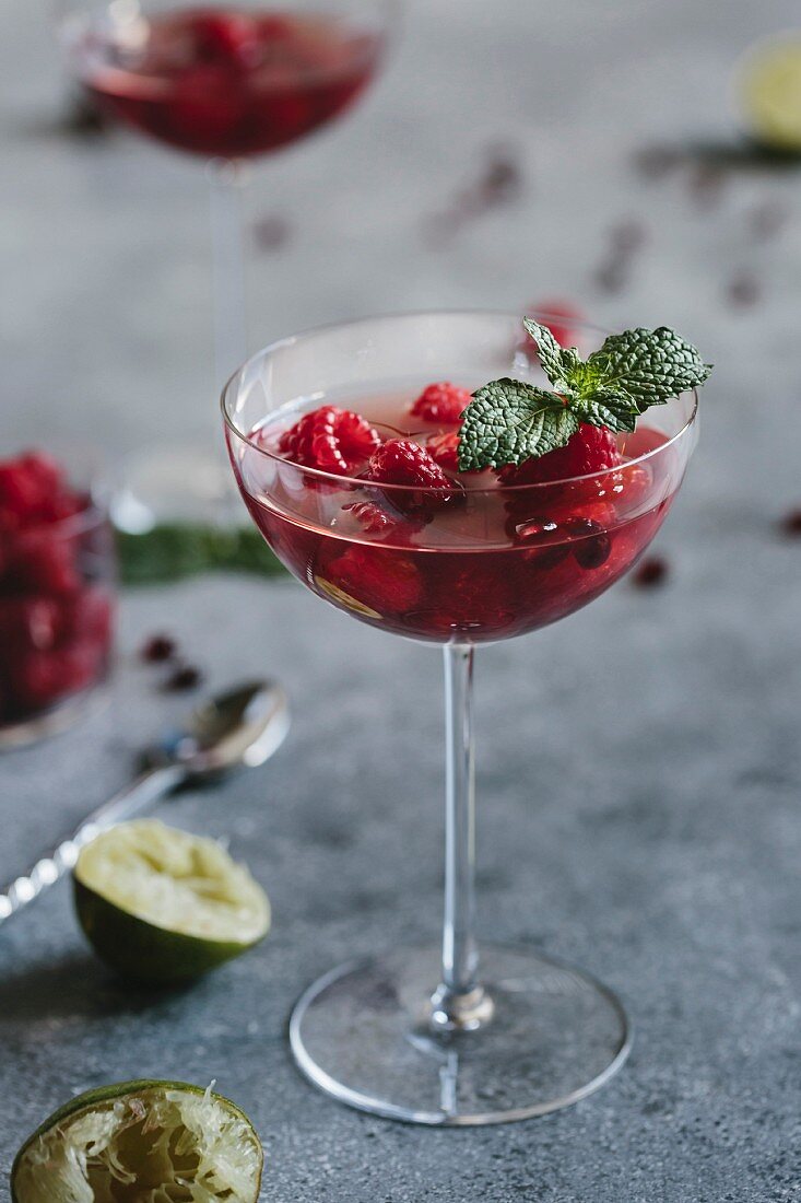 A coupe glass of Raspberry and Pomegranate Champagne Cocktailed garnished with mint