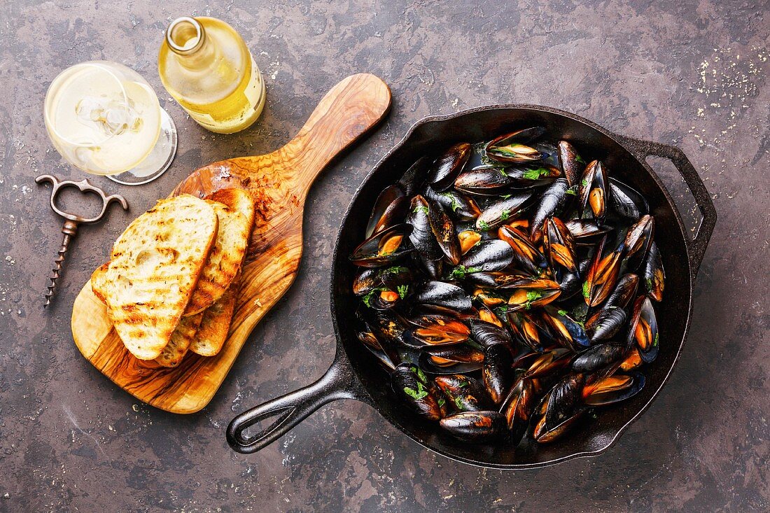 Mussels on frying pan, Bread toasts and Wine on dark background