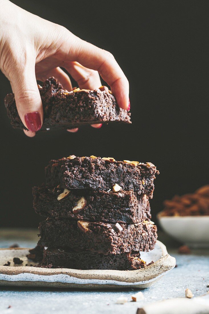 A woman is taking a piece of Dark Chocolate and Almond Butter Brownies with Sea Salt