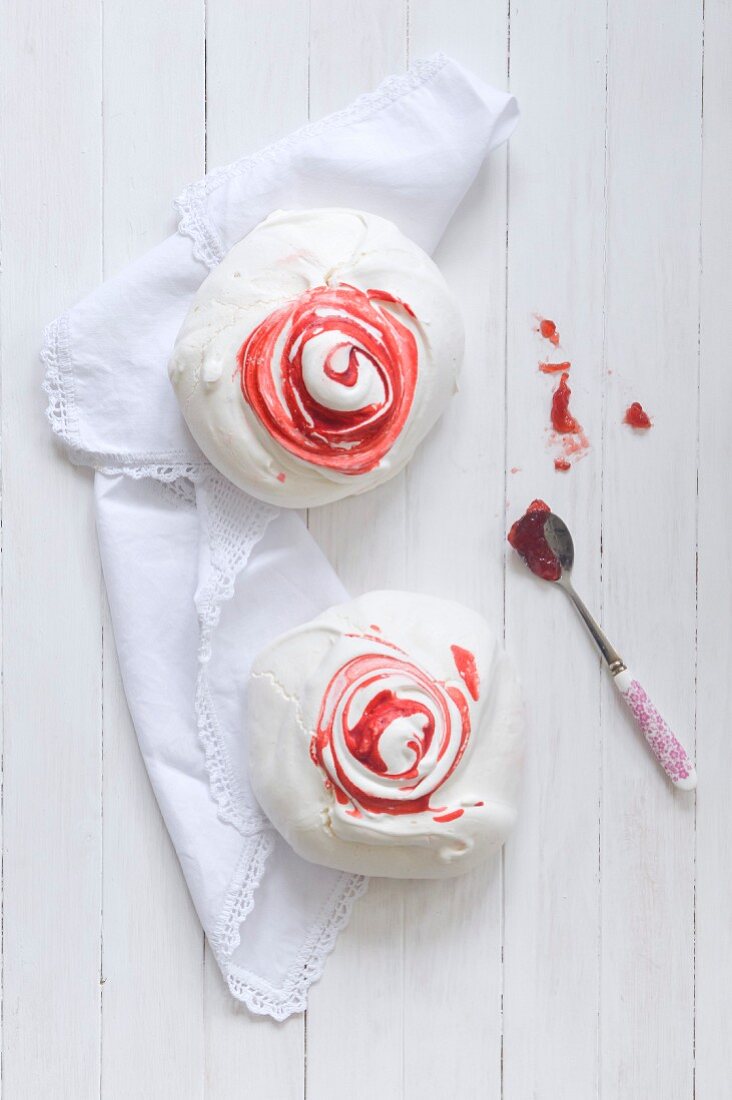 Large strawberry meringues with spoon of jam